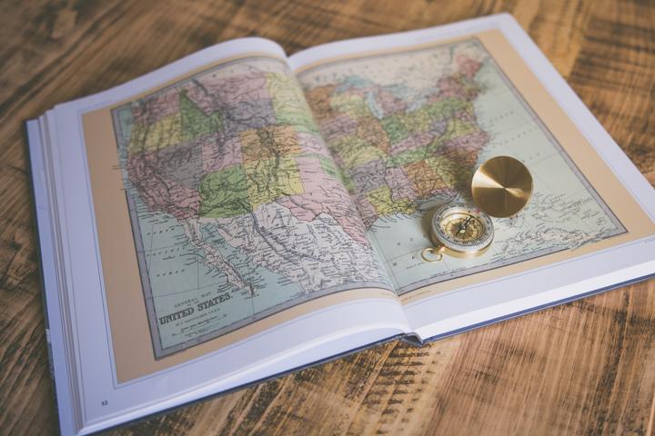 open history book with a map of the United States and a compass